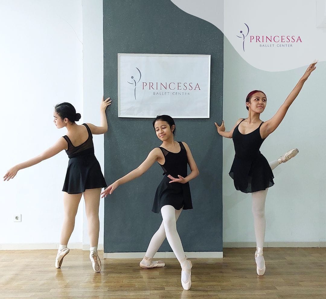Dancers posing in black leotards and pointe shoes at the studio